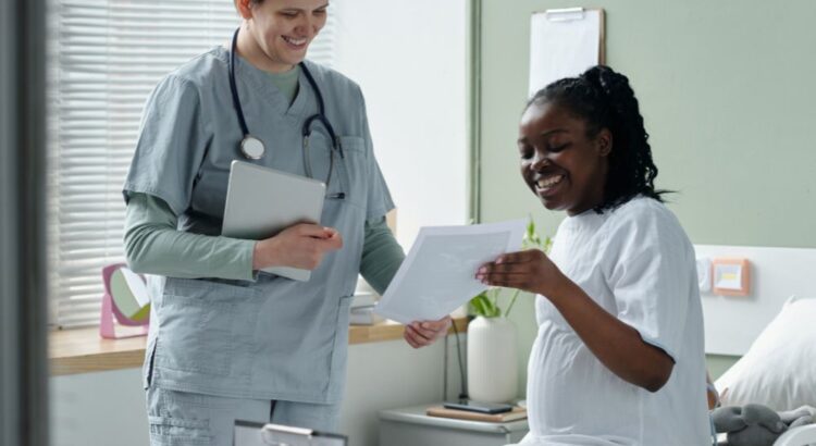 Profissional de saúde conversa com paciente gestante em quarto hospitalar, analisando resultados de exames e orientando sobre acompanhamento médico.